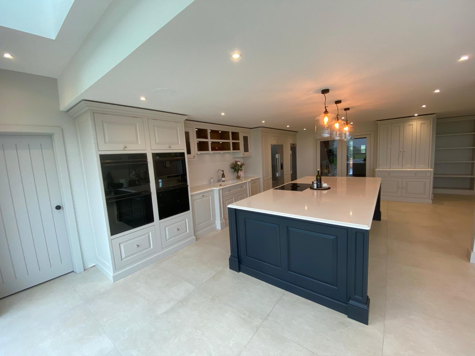 Grand bespoke kitchen with navy island and pendant lights in Cambridgeshire by Cromwell Interiors